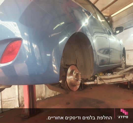 רכב כחול על ליפט במוסך עם גלגל אחורי מפורק